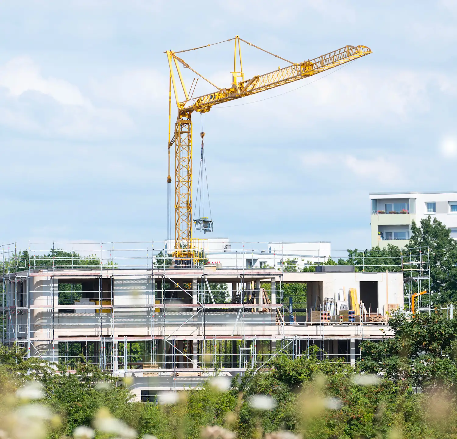 Neubau-Baustelle mit Kran und Rohbau eines modernen Wohngebäudes.