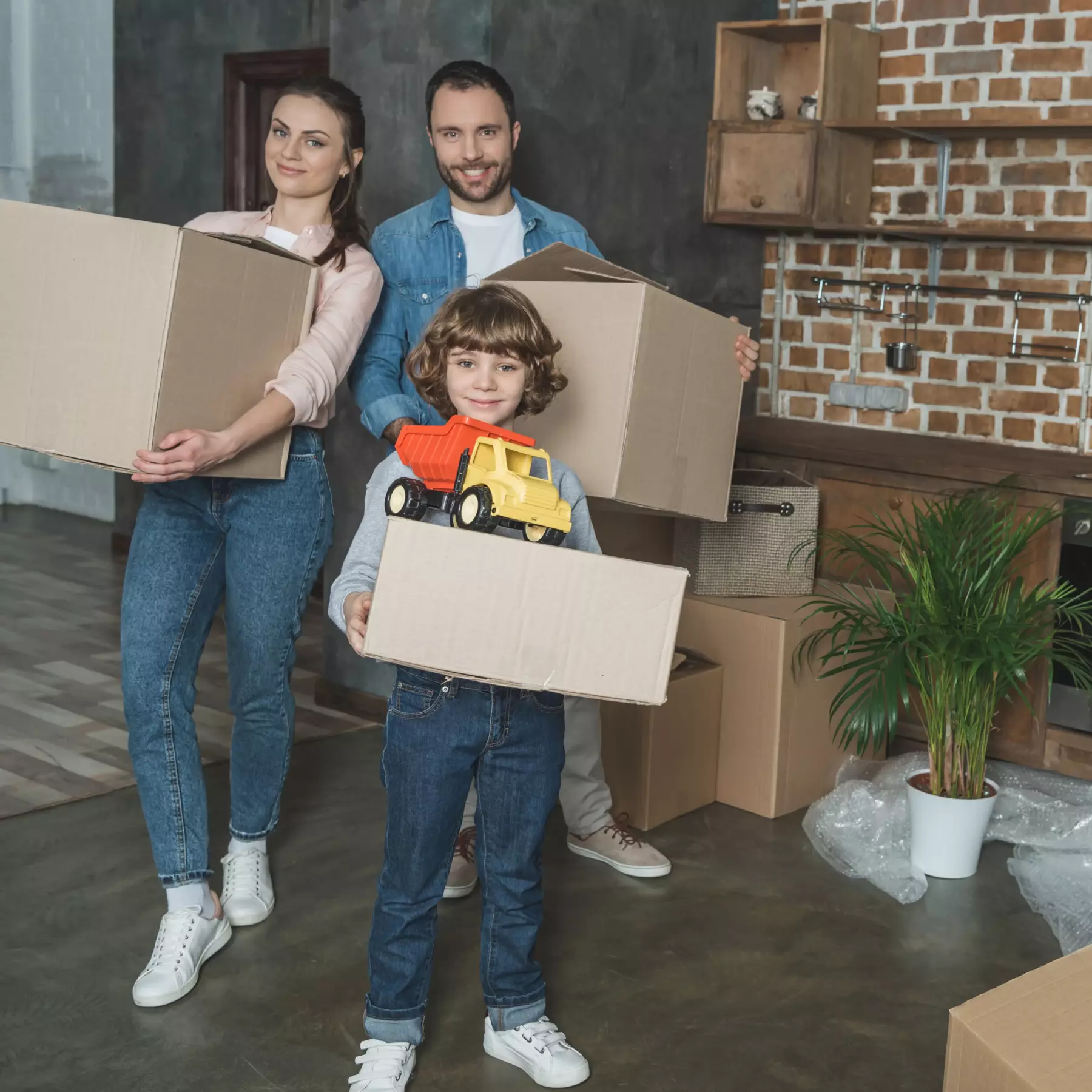 Lächelnde Familie steht mit Umzugskartons in einem neuen Zuhause.