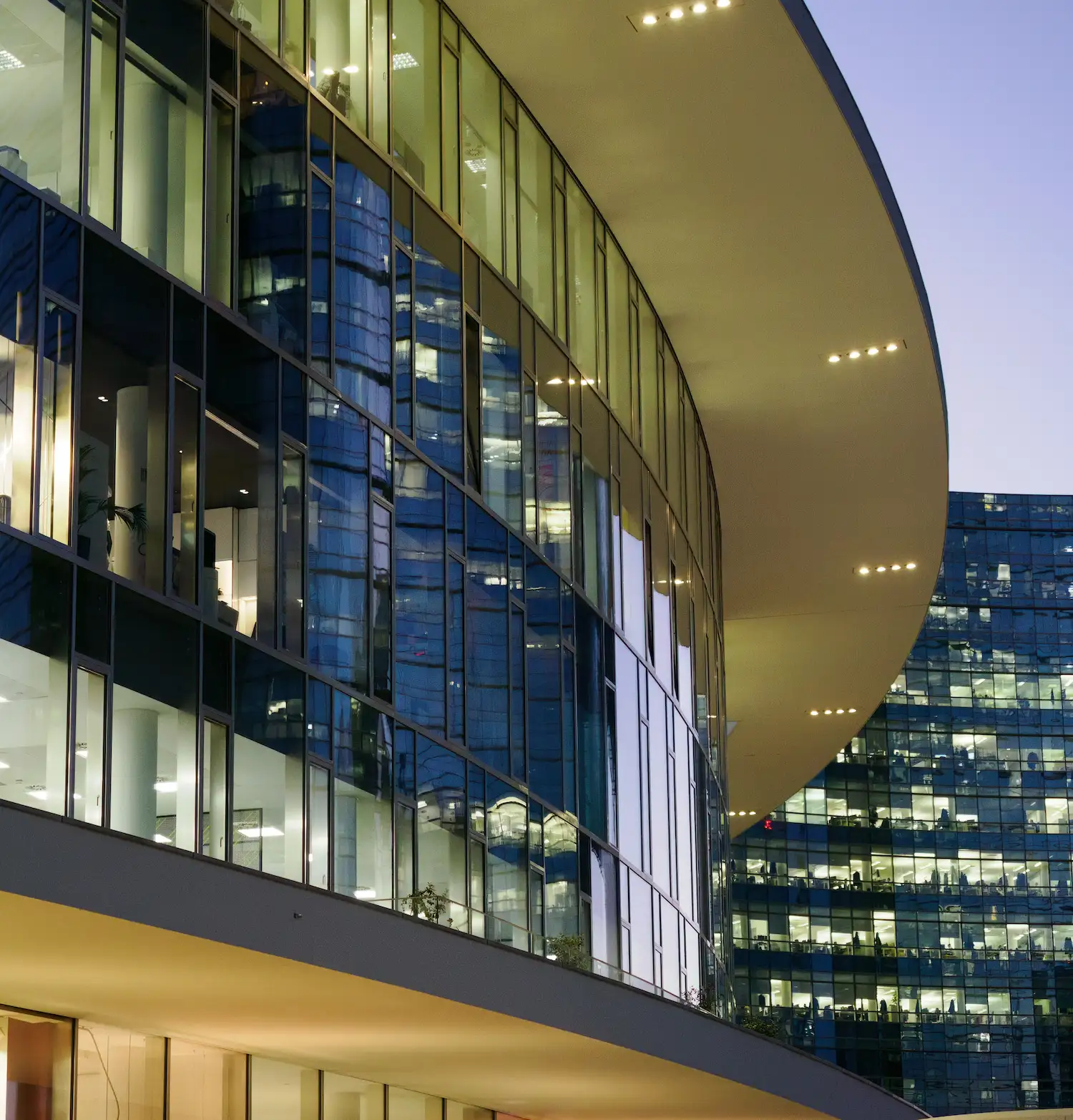 Geschwungene moderne Glasarchitektur im Stadtteil Porta Nuova in Mailand bei Abendlicht.
