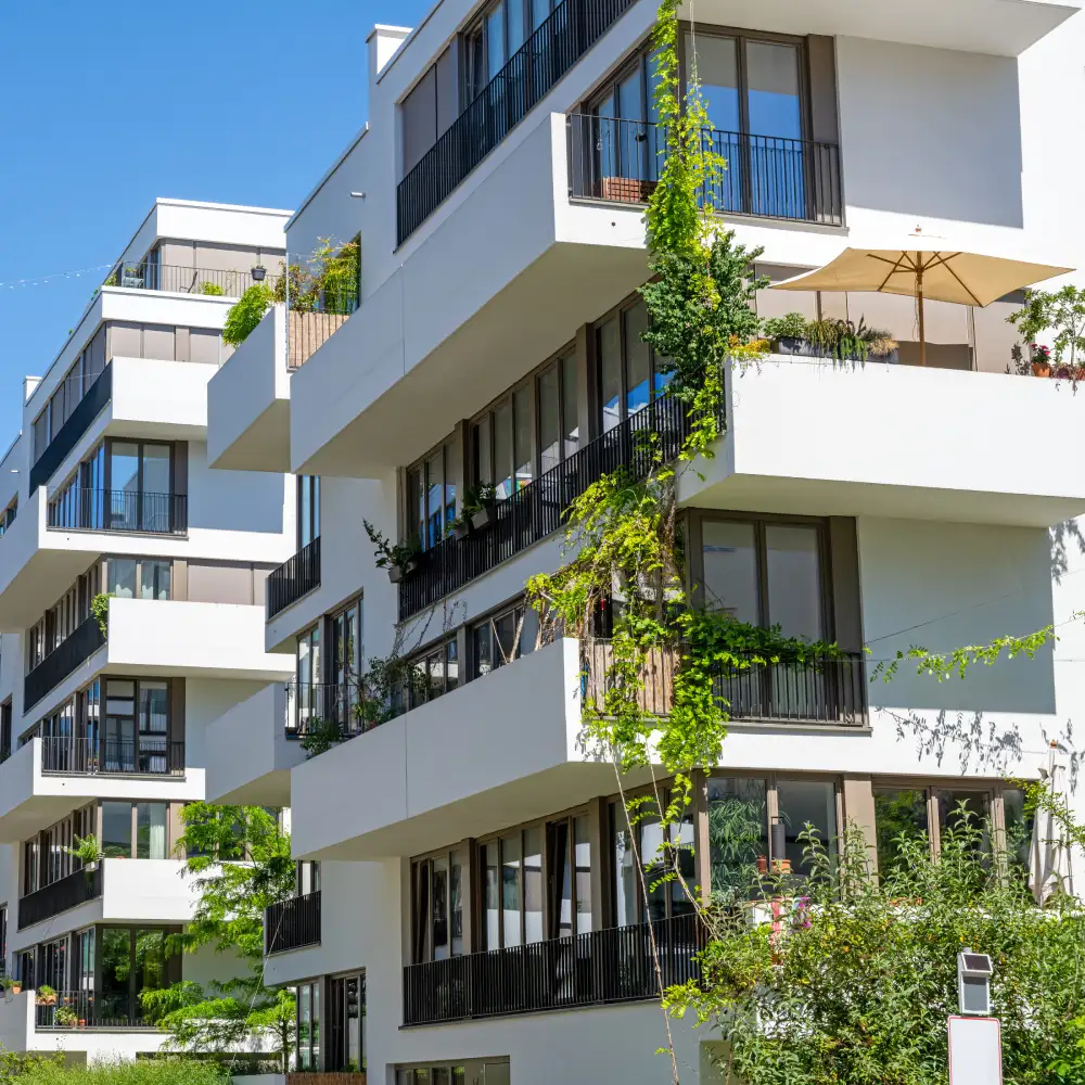 Moderne mehrstöckige Apartmenthäuser mit Balkonen, Begrünung und heller Fassade.