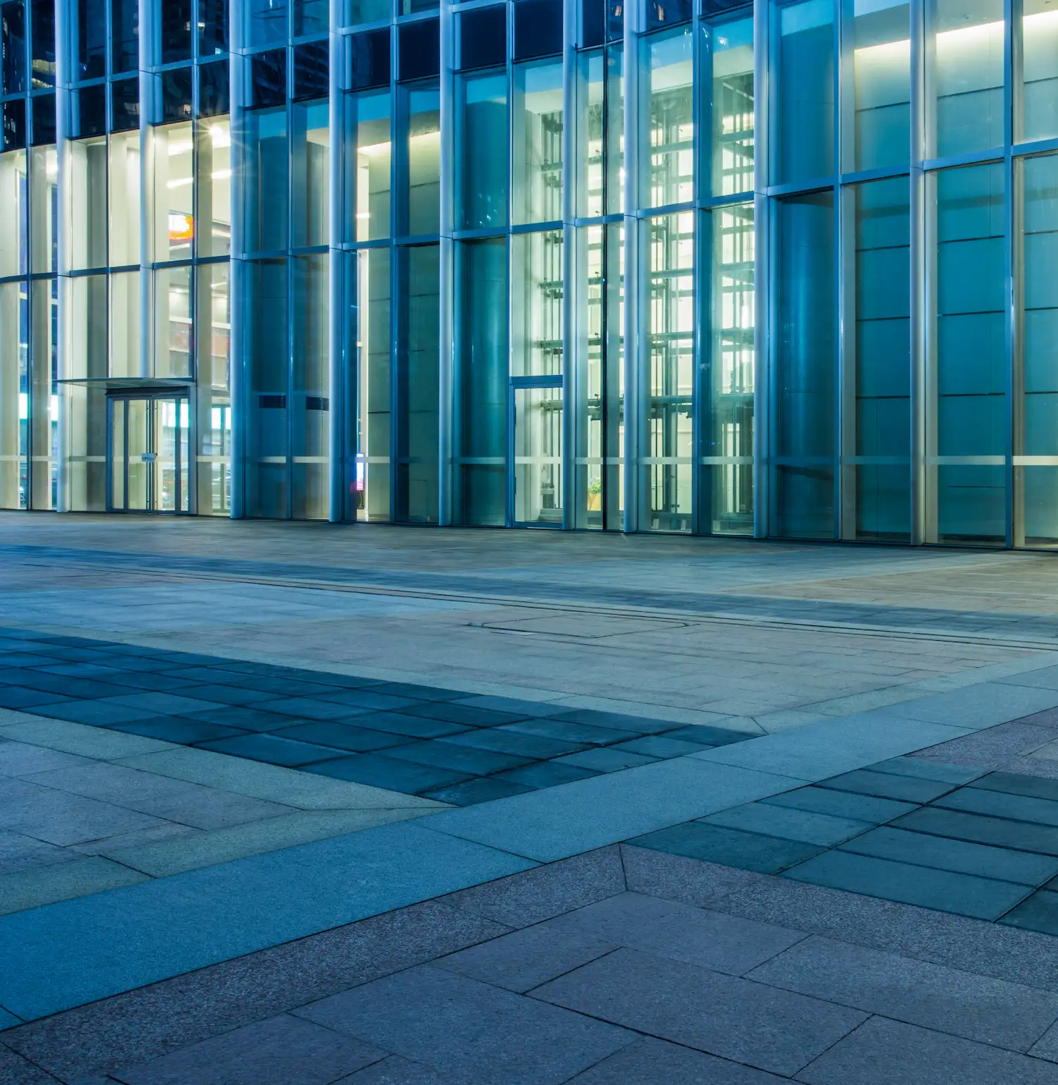 Große blaue Glasfassade und Eingangsbereich eines modernen Geschäftsgebäudes.