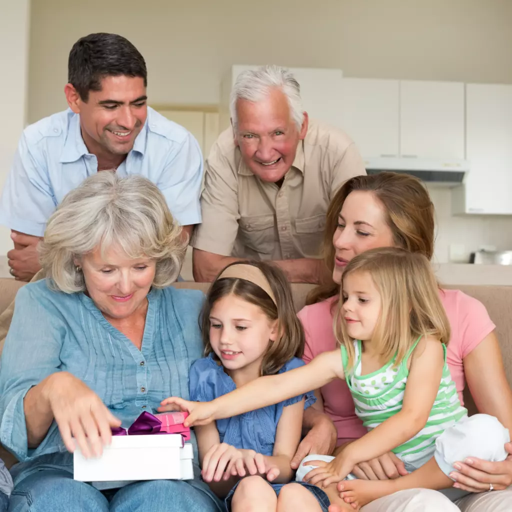 Mehrere Familienmitglieder sitzen zusammen und freuen sich über ein Geschenk.