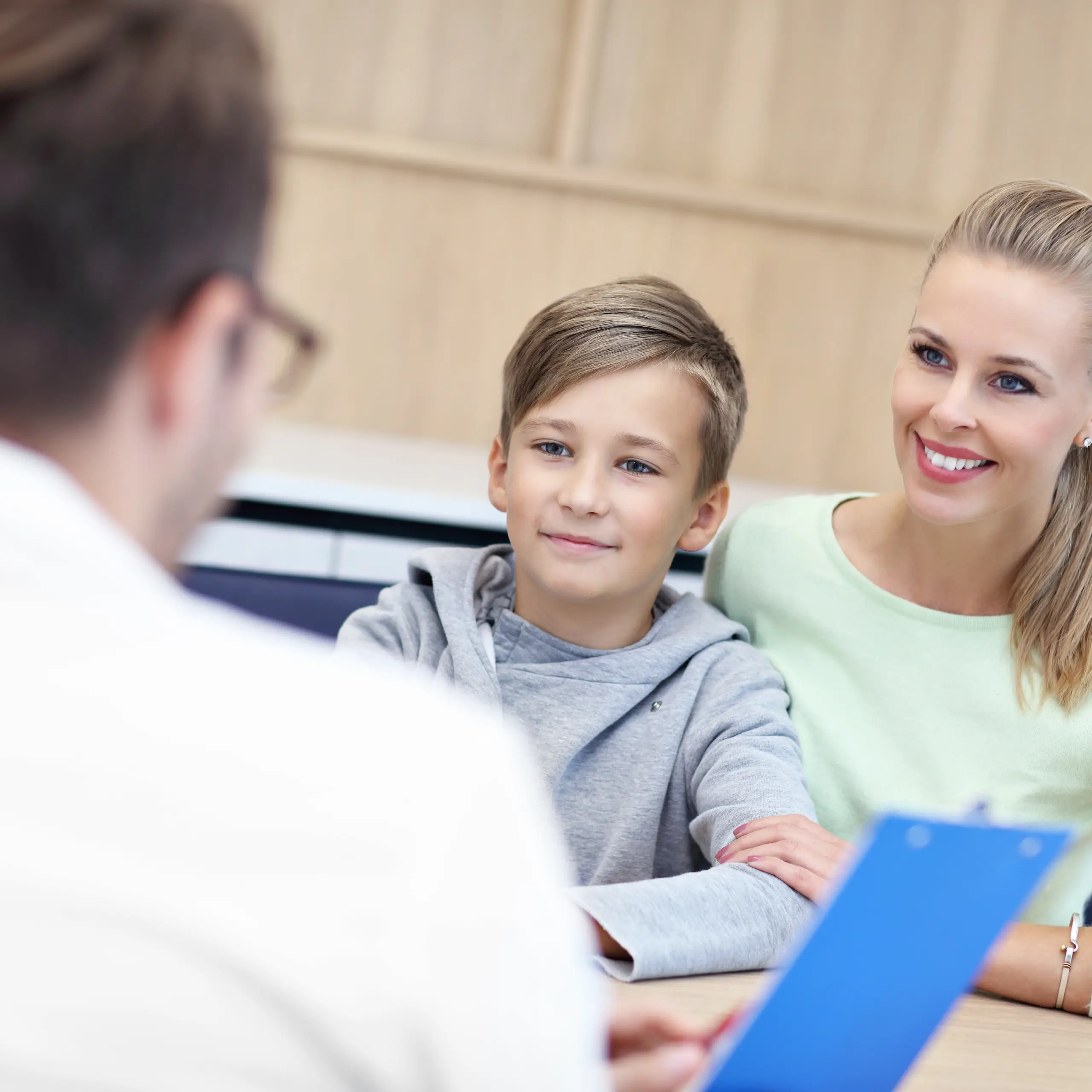 Kleiner Junge sitzt mit seiner Mutter bei einer Untersuchung in einer Arztpraxis.