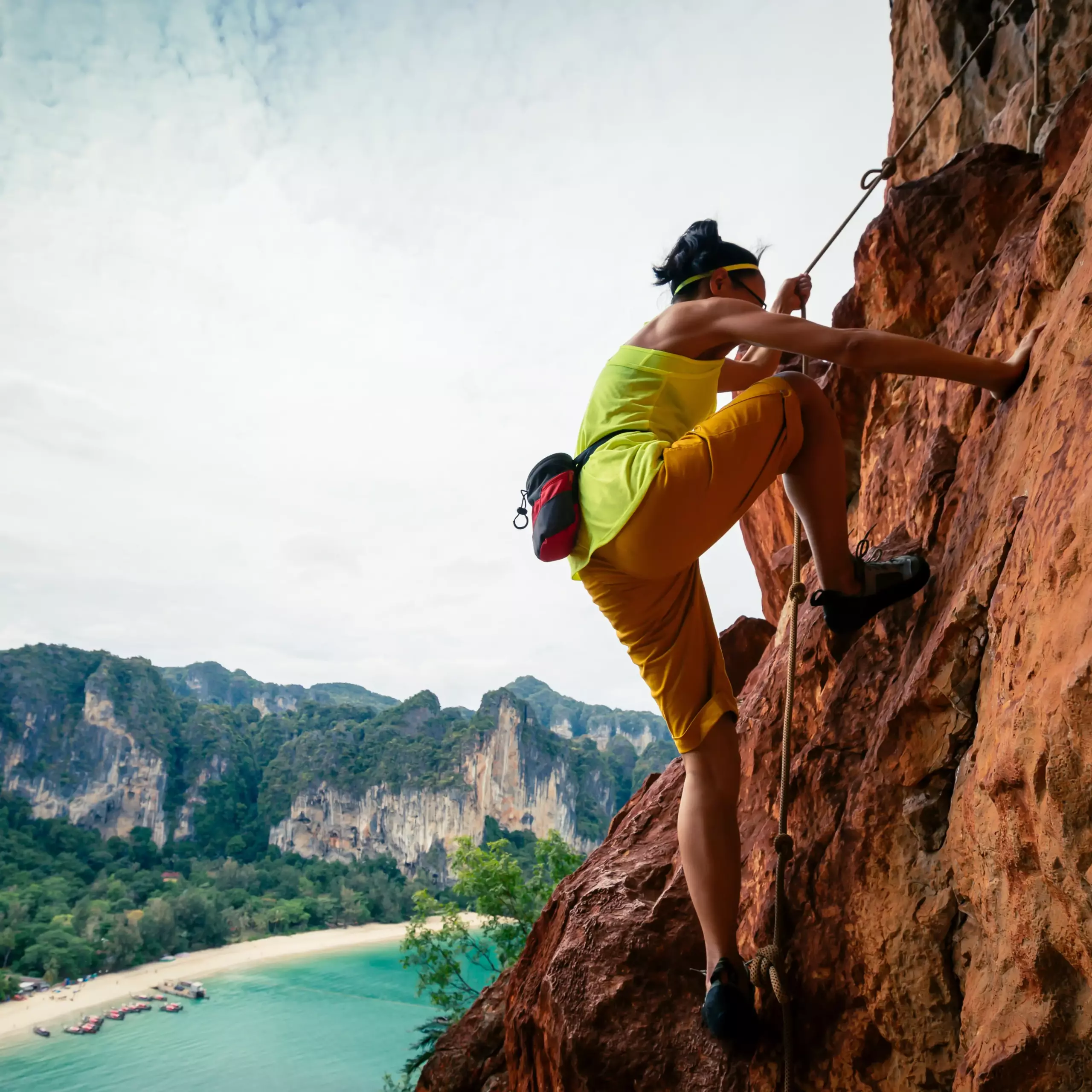 Person klettert mit Sicherung an einer steilen Felswand in der Natur.