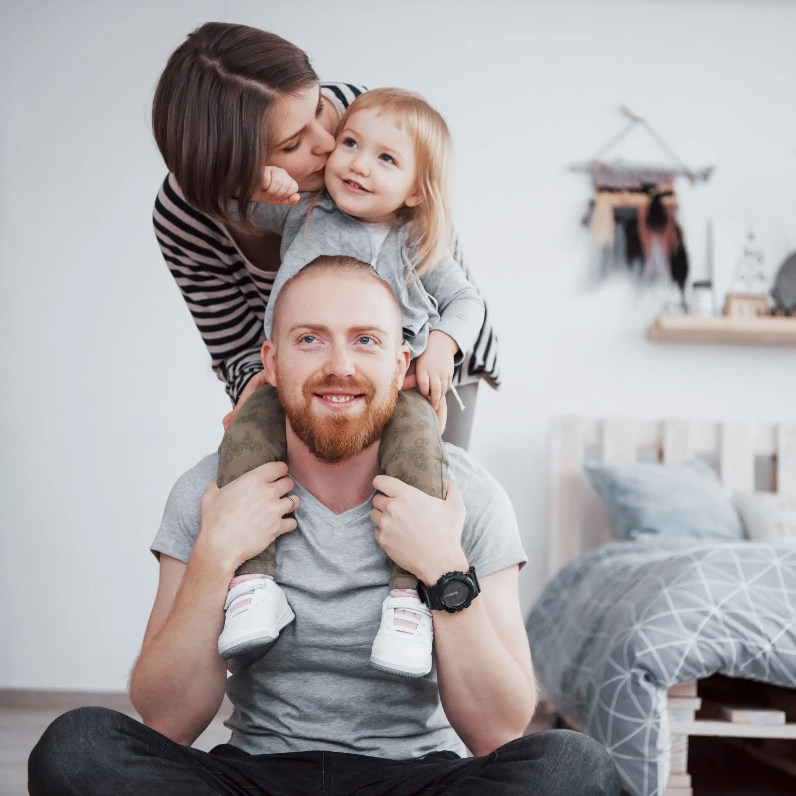 Vater sitzt mit seinen Kindern zusammen; ein Kind sitzt auf seinen Schultern.